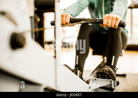 Junger Mann Training am Rudergerät in der Turnhalle Stockfoto