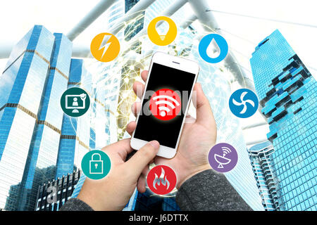 Smart Building und Internet der Dinge-Konzept. Hand halten Smartphone. Technologie-Symbole auf Office-Gebäude und Drahtmodell-Welt zu verbinden, mit abstrakten Stockfoto