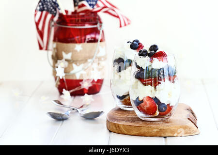 Trifle mit Heidelbeeren, Erdbeeren, Schlagsahne und Sterne geformte Sandkuchen mit amerikanischen Flaggen im Hintergrund gemacht. Geringe Schärfentiefe mit se Stockfoto