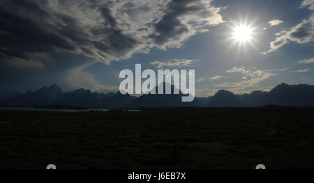 Blauer Himmel, die dunklen Stratocumulus Wolken sehen, südlich von Jackson Lake Lodge, der Teton Range mit Sonnenstrahlen Sonne versinken in Richtung Doane Spitze, Wyoming, USA Stockfoto