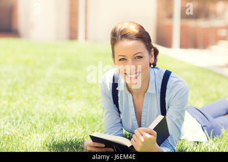 Glückliche Studentin aufgeregt, zurück zur Schule-Universität bekommen. Schöne Frau Buch zu lesen, Festlegung auf dem grünen Rasen, Campus der Universität. Studentin