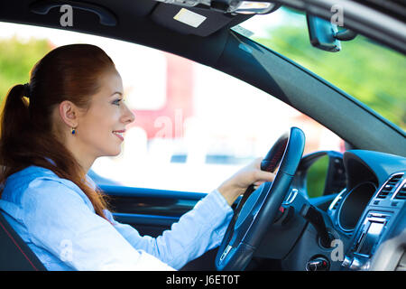 Porträt, Lächeln, attraktive Brünette Frau, angeschnallt, fahren, testen ihr neues schwarzes Auto, Automobil, Autohaus, isolierte Straße, Cit gekauft Stockfoto