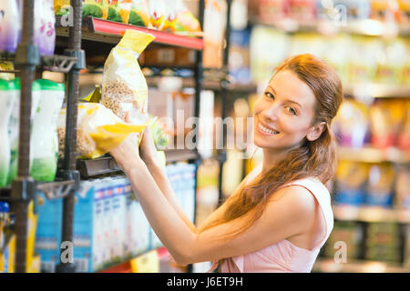 Closeup Portrait schöne attraktive junge, glücklich, lose lächelnde Frau shopping für Getreide, in Lebensmittel Supermarkt. Positive Mimik, emoti Stockfoto