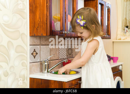 Aktive kleine Vorschule Alter Kind, niedlichen Kleinkind Mädchen mit blonden lockigen Haaren, Shows spielen Küche, Holz, spielt in der Küche Stockfoto