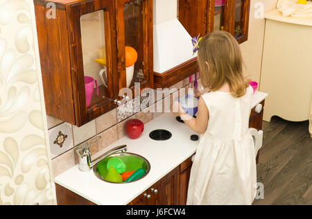 Aktive kleine Vorschule Alter Kind, niedlichen Kleinkind Mädchen mit blonden lockigen Haaren, Shows spielen Küche, Holz, spielt in der Küche Stockfoto