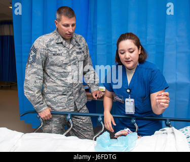 US Air Force Airman 1.Klasse, Dezina Khosroabadi mit der 60. chirurgische Operations Squadron, Travis Air Force Base in Kalifornien, erklärt ihre Pflichten Chief Master Sgt. Steve Nichols, 60. Air Mobility Wing Befehl Chef, während der Arbeiten mit Flieger Programm, 12. Mai 2017. Das Programm beinhaltet Flügel Führung Interaktion mit Flieger zu bekommen einen detaillierten Überblick über jede Mission an Travis durchgeführt. (U.S. Air Force Photo/Louis Briscese) Stockfoto