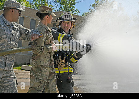 Ein Soldat mit der Indiana National Guard 719th Ingenieur Feuerwehrmann Ablösung Sitz zeigt Spc. Roy Lopez der 206. Broadcast Operations Abteilung und Pfc. Anamarie Fajardo 205. Press Camp Sitz wie ein Feuerwehrschlauch effektiv während der Feuerwehrmann Ausbildung im Muscatatuck Urban Training Center, Mai 13 bedient. (Foto: Pvt. Justine Gutierrez, 205. Press Camp Hauptquartier US Army Reserve) Stockfoto