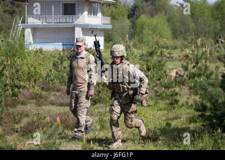 Ein Yavoriv GÜZ-Trainer beobachtet und betreut einen ukrainischen Soldaten aus dem 1. Airmobile Bataillon, 79. Air Assault Brigade während er ein paar Bewegung Training Lane bei Yavoriv CTC International Peacekeeping und Security Center in der Nähe von Yavoriv, Ukraine, am 15. Mai durchläuft.    Yavoriv CTC-Personal zusammen mit Mentoren aus der US-Armee 45. Infantry Brigade Combat Team, führte Paare Bewegungstraining für Soldaten von der 1-79. während der Rotation des Bataillons durch Yavoriv CTC. 45. ist die Ukraine als Teil der gemeinsamen multinationalen Training Group-Ukra bereitgestellt. Stockfoto