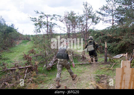 Ukrainische Soldaten aus dem 1. Airmobile Bataillon, 79. Air Assault Brigade eilt zu decken, während ein Yavoriv GÜZ-Trainer beobachtet und Feedback während Paare Bewegung Training Lane bei Yavoriv CTC International Peacekeeping und Security Center in der Nähe von Yavoriv, Ukraine, am 15. Mai liefert.    Yavoriv CTC-Personal zusammen mit Mentoren aus der US-Armee 45. Infantry Brigade Combat Team, führte Paare Bewegungstraining für Soldaten von der 1-79. während der Rotation des Bataillons durch Yavoriv CTC. 45. ist die Ukraine als Teil der gemeinsamen multinationalen Zug bereitgestellt. Stockfoto