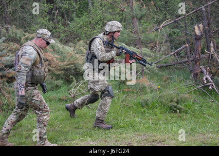 Ein Yavoriv GÜZ-Trainer beobachtet und betreut einen ukrainischen Soldaten aus dem 1. Airmobile Bataillon, 79. Air Assault Brigade während er ein paar Bewegung Training Lane bei Yavoriv CTC International Peacekeeping und Security Center in der Nähe von Yavoriv, Ukraine, am 15. Mai durchläuft.    Yavoriv CTC-Personal zusammen mit Mentoren aus der US-Armee 45. Infantry Brigade Combat Team, führte Paare Bewegungstraining für Soldaten von der 1-79. während der Rotation des Bataillons durch Yavoriv CTC. 45. ist die Ukraine als Teil der gemeinsamen multinationalen Training Group-Ukra bereitgestellt. Stockfoto