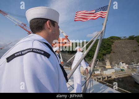 170516-N-OY799-137 YOKOSUKA, Japan (16. Mai 2017) Segler Standby, der Fähnrich auf dem Flugdeck des Flugzeugträgers USS Ronald Reagan (CVN-76) zu senken. Ronald Reagan ist das Flaggschiff der Carrier Strike Group 5, Bereitstellung einer kampfbereit Kraft, die schützt und verteidigt die kollektiven maritime Interessen seiner Verbündeten und Partner in der Indo-Asien-Pazifik-Region.  (Foto: U.S. Navy Mass Communications Specialist 2. Klasse Kenneth Abbate/freigegeben) Stockfoto