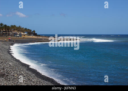 Ein blauer Himmel über den felsigen Strand und Bucht am Playa Las Americas mit der Brandung am Ufer brechen Stockfoto