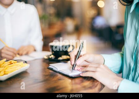 zwei Frauen, die in ihre Notizen in einem Coffee-shop Stockfoto