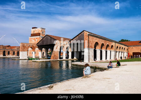 Venice,Castello,Arsenale.57th Biennale in Venedig 2017, La Biennale di Venezia.Art Liebhaber an die Arsenale-Hafen, historischen Backsteinbauten & Boot Schuppen sitzen Stockfoto