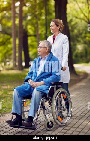 Porträt der ältere Mann im Rollstuhl mit Bezugsperson Krankenschwester im freien Stockfoto