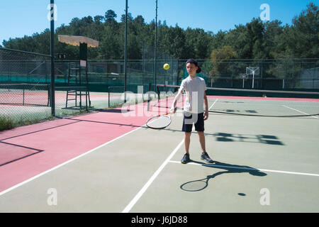 Junge mit Schläger am Tennisplatz. Sonniger Tag im Sommer Stockfoto