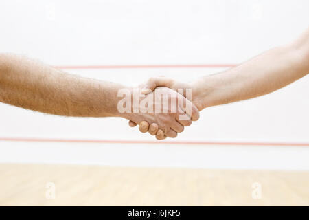 Handshake vor Spiel im Squash. Zwei Männer sind gonna Sport Kampf haben. Foto mit selektiven Fokus. Squash-Spieler schütteln Hand vor Spiel in co Stockfoto