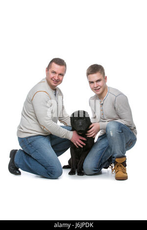 Vater und Sohn sitzen mit schwarzen Shar pei Hund. Studio gedreht isolierten auf weißen Hintergrund. Kopieren Sie Raum. Stockfoto