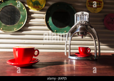 Manuelle Oldschool Espresso Maker Maschine mit einer Tasse auf Holztisch im schönen Morgenlicht Stockfoto