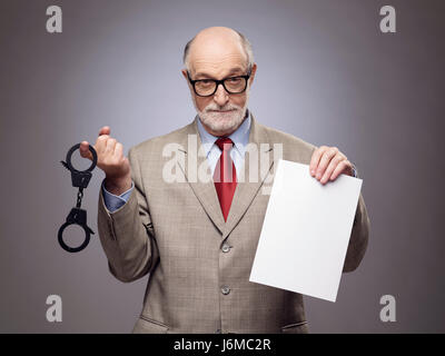 Senior Business-Mann mit Handschellen und leere Vertrag Papier Hinweise auf Gefahr der Wirtschaftskriminalität Stockfoto