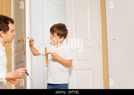 Porträt der glückliche junge Vater und Kind Sohn Installation Tür Griff zusammen Stockfoto