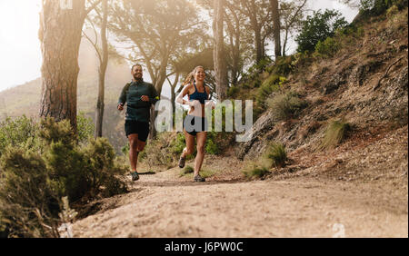 Junge Menschen Trailrunning auf einem Bergpfad. Zwei Läufer im Morgen trainieren. Stockfoto