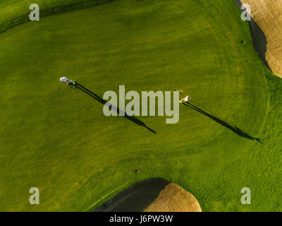 Luftaufnahme der Golfer spielen auf Putting Green. Professionelle Spieler auf einem grünen Golfplatz. Stockfoto