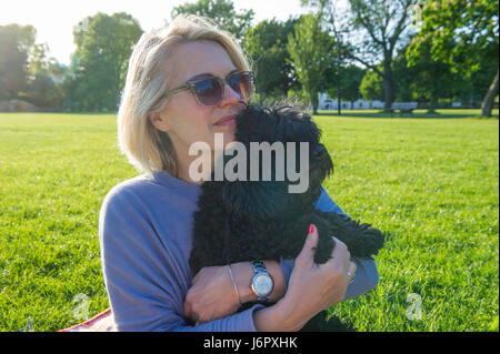 Eine Frau mittleren Alters auf ein Picknick mit ihrem kleinen schwarzen Hund Stockfoto