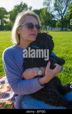 Eine Frau mittleren Alters auf ein Picknick mit ihrem kleinen schwarzen Hund Stockfoto