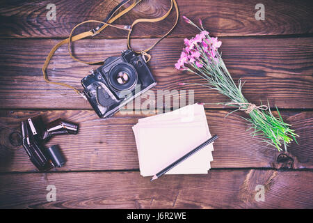 Blank Grußkarte und alte Vintage Filmkamera auf braunem Hintergrund aus Holz, Draufsicht, Vintage Muskelaufbau Stockfoto