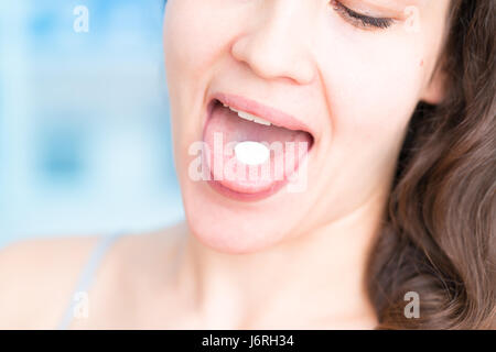 Junge Frau, die Einnahme einer Tablets. Gesicht des Mädchens hautnah mit einer Pille auf der Zunge, isoliert auf einem weißen Hintergrund. Stockfoto