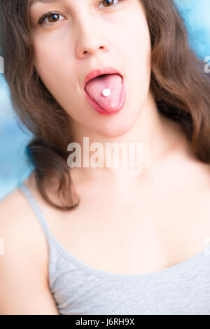 Junge Frau nimmt eine Pille. Süße junge Frau, die ihre Zunge mit Pille drauf Stockfoto