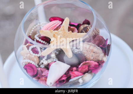 leicht verschmutzte Sterne, dafГјr Perlen liegen transparent für eine Glasvase mit violett und rosa Blüten. Stockfoto