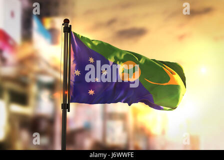 Christmas Island Flagge gegen City unscharf Hintergrund bei Sonnenaufgang Hintergrundbeleuchtung Stockfoto