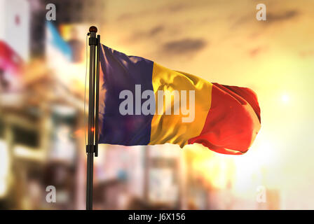 Rumänien-Flagge gegen City unscharf Hintergrund bei Sonnenaufgang Hintergrundbeleuchtung Stockfoto