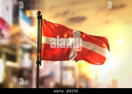 Sovereign Military Order of Malta Flagge gegen City unscharf Hintergrund bei Sonnenaufgang Hintergrundbeleuchtung Stockfoto