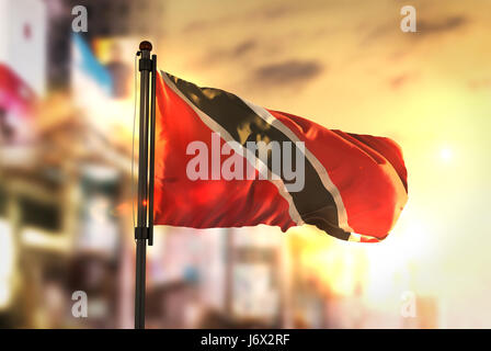 Trinidad und Tobago Flagge gegen City unscharf Hintergrund bei Sonnenaufgang Hintergrundbeleuchtung Stockfoto