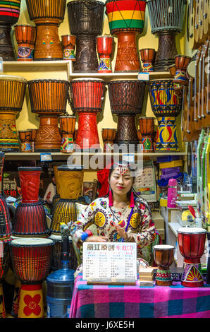 Lijiang, China - April 10,2017: ein chinesisches Mädchen spielen die Djembe im Einzelhandel befindet sich in der Altstadt von Lijiang in der Provinz Yunnan, China Stockfoto