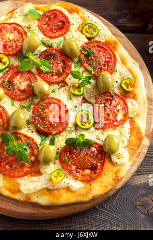 Italienische Pizza mit Tomaten, Paprika, grüne Oliven, Oregano und Mozzarella-Käse hautnah. Frische hausgemachte Gemüse Pizza. Stockfoto