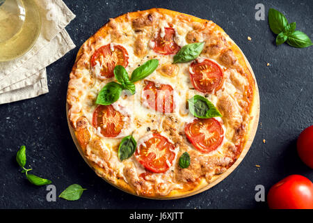 Pizza Margherita auf schwarzem Stein, Ansicht von oben. Pizza Margarita mit Tomaten, Basilikum und Mozzarella-Käse hautnah. Stockfoto