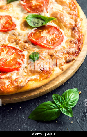 Pizza Margherita auf schwarzem Stein. Pizza Margarita mit Tomaten, Basilikum und Mozzarella-Käse hautnah. Stockfoto