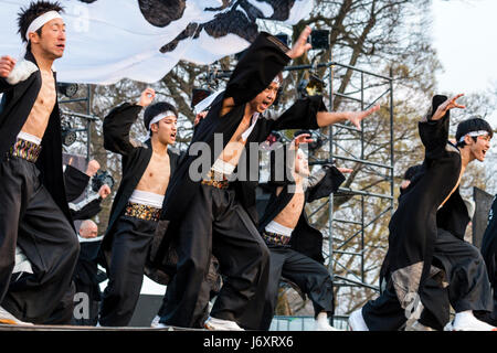 Yosakoi junge männliche Tänzer in Schwarz happi Mäntel und weiße Stirnbänder tanzen auf der Open Air Bühne in Kumamoto, Japan. Stockfoto