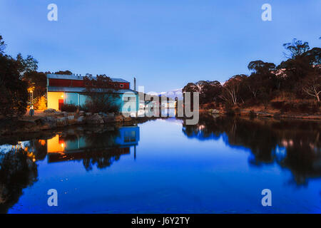 Einsamen Hochgebirge Crackenback See in THredbo Tal des Snowy-Mountains-Nationalpark bei Sonnenaufgang, wenn blaue Himmel in stehenden Gewässern mit Hil spiegelt Stockfoto