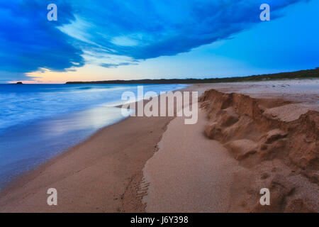 Sandigen Strand von South Durras an Südküste in New South Wales, Australien, bei Sonnenaufgang. Einlaufenden Wellen untergraben Mini Sanddünen am Strand. Stockfoto