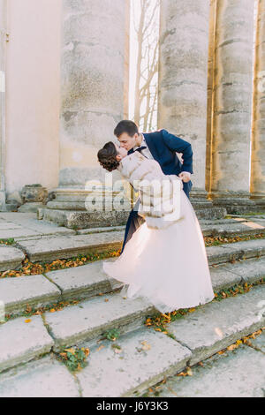 Das Full-length Blick auf das frisch vermählte Paar küssen auf der Treppe des alten Gebäudes. Stockfoto