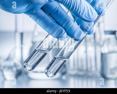 Labor-Becher in der Hand des Analytikers in Kunststoff-Handschuh. Stockfoto