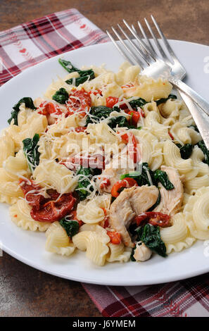 Warmer Salat Nudeln mit Huhn, Sonne getrocknet, Tomaten, Spinat, Paprika und aromatisierte Parmesan-Käse Stockfoto