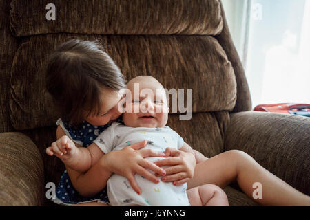 Mädchen sitzen im Sessel Kuscheln ein Baby boy Stockfoto