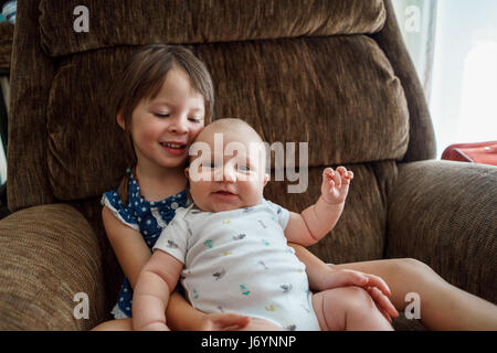 Mädchen sitzen im Sessel Kuscheln ein Baby boy Stockfoto