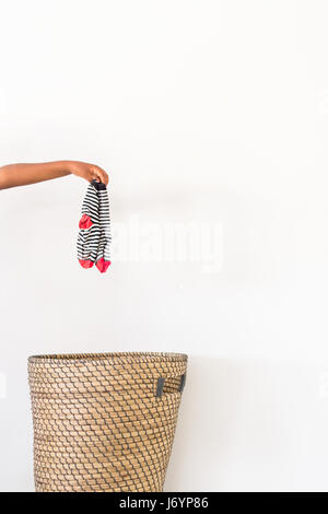 Hand setzen schmutzige Socken in den Wäschekorb Stockfoto